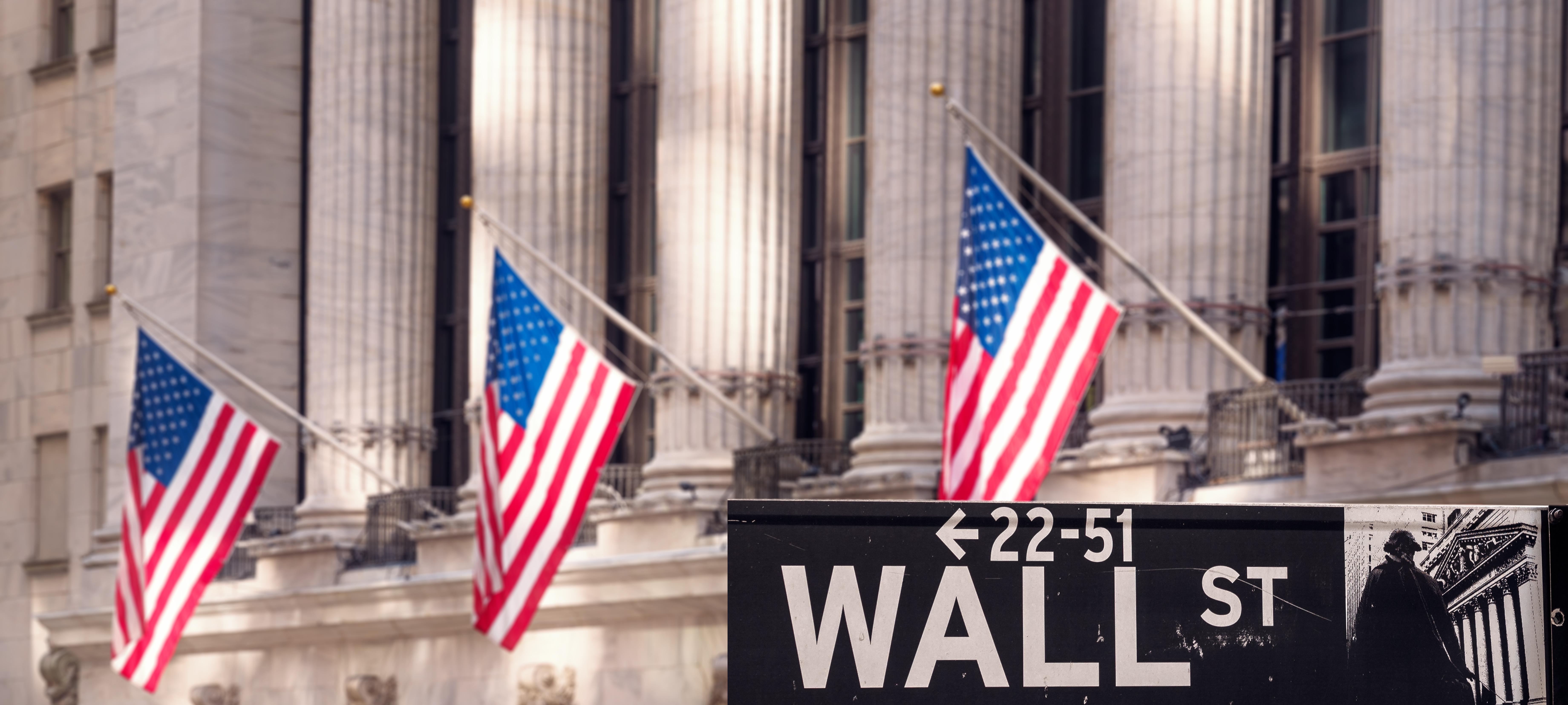 Wall Street sign in front of building with American flags