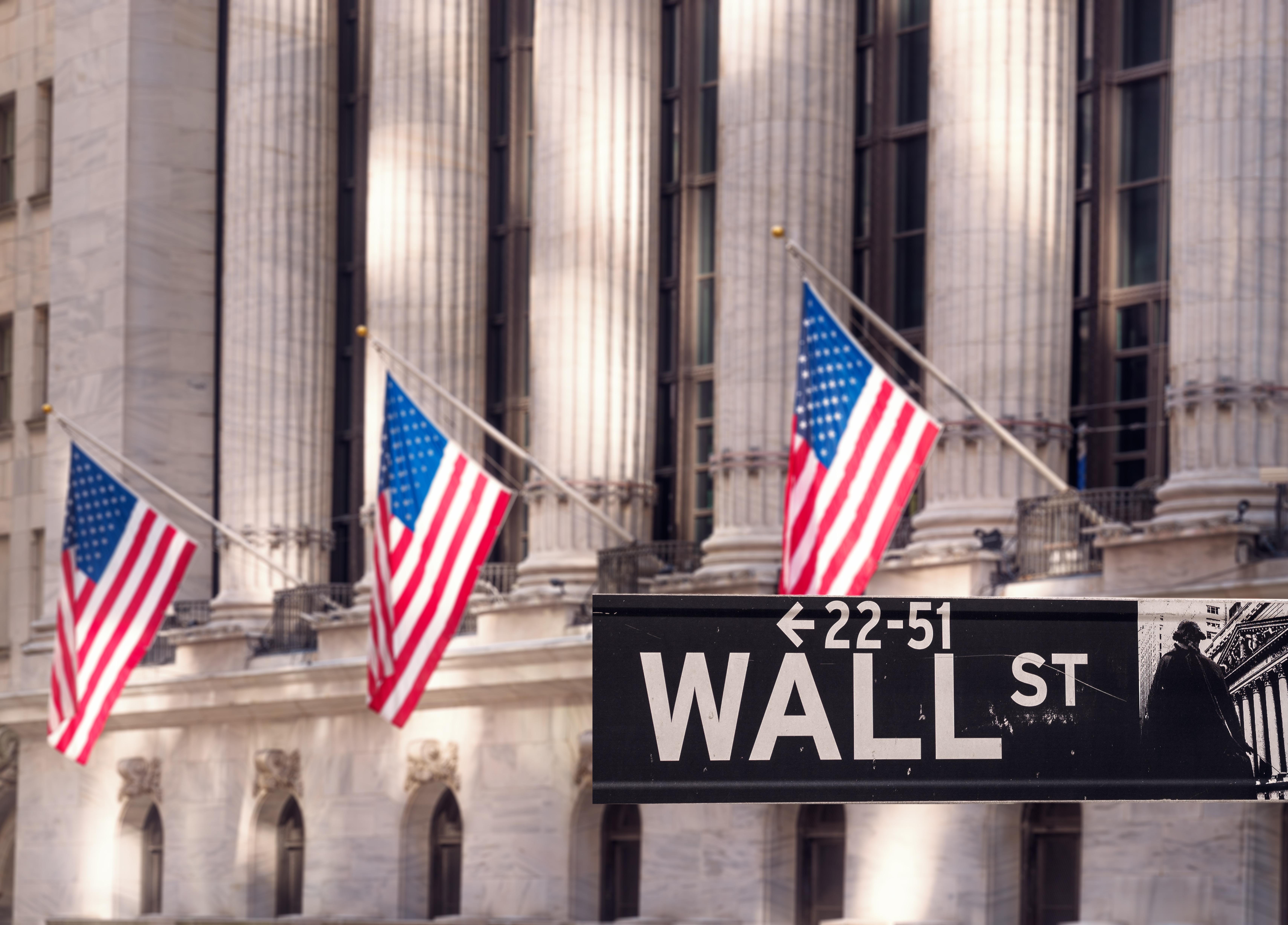 Wall Street sign in front of building with American flags